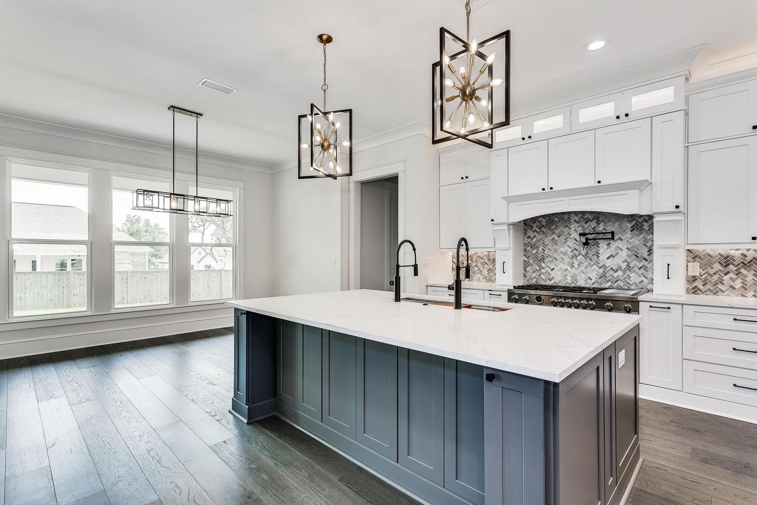 A luxury kitchen with a large island, dual-faucet sink and chandeliers